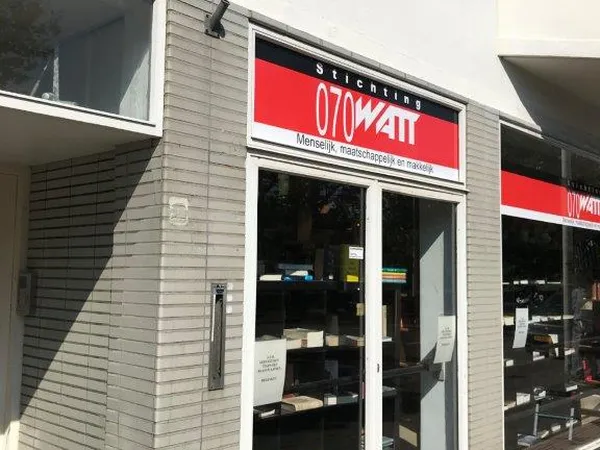 Winkelpui van 070watt kringloopwinkel met rode en zwarte letters op gevel, glazen deuren en ramen met uitzicht op winkelinter
