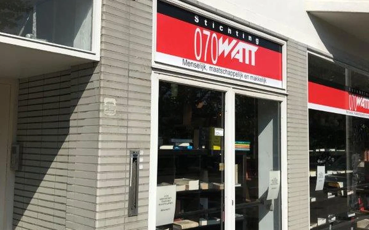 Winkelpui van 070watt kringloopwinkel met rode en zwarte letters op gevel, glazen deuren en ramen met uitzicht op winkelinter