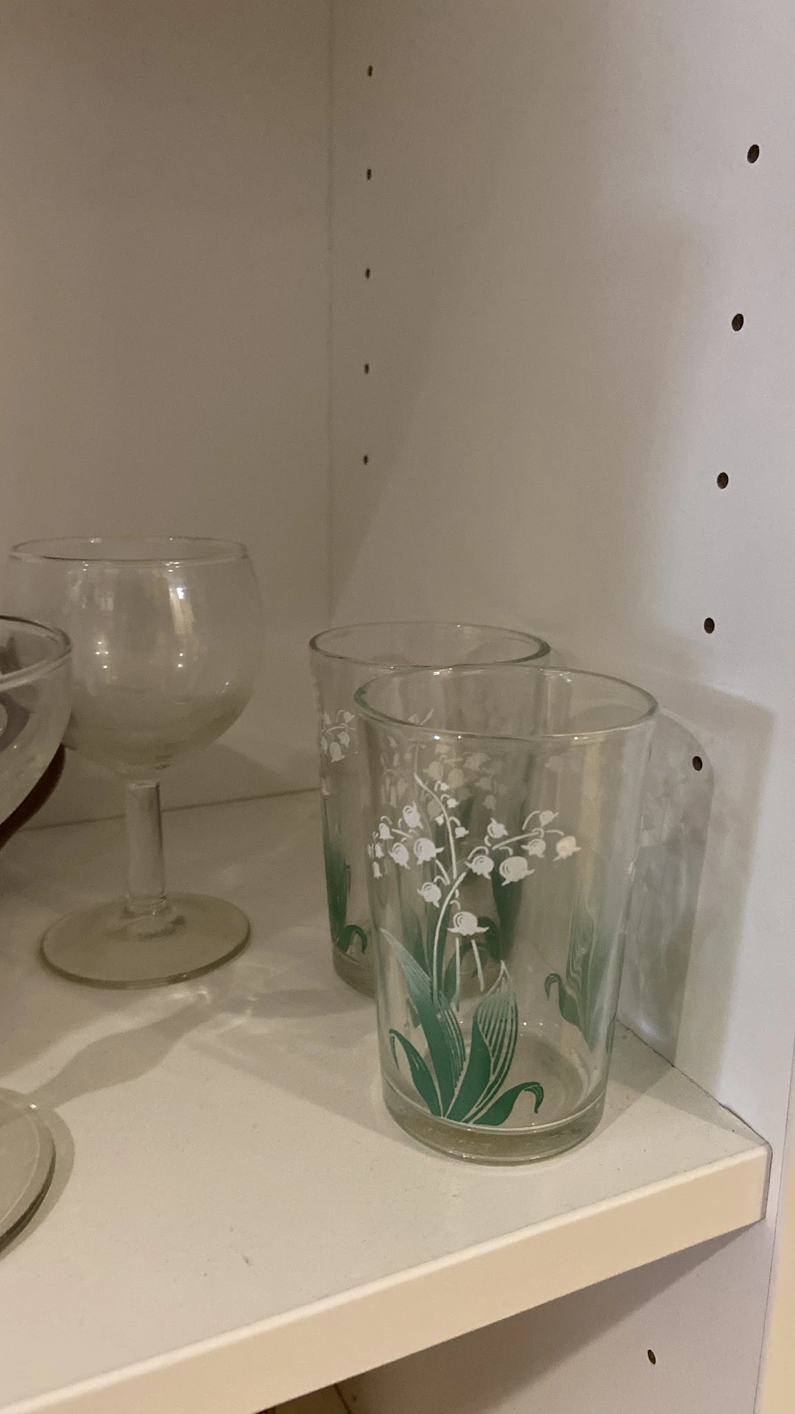 Glazen met witte bloemmotieven en lege wijnglazen op een witte achtergrond