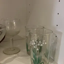 Glazen met witte bloemmotieven en lege wijnglazen op een witte achtergrond