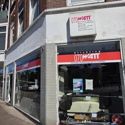 Winkelgevel van kringloopwinkel 070watt met rood-wit logo en donkere etalageruiten