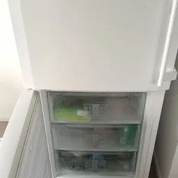 Binnenkant van een open koelkast met lege schappen en groene oppervlakken