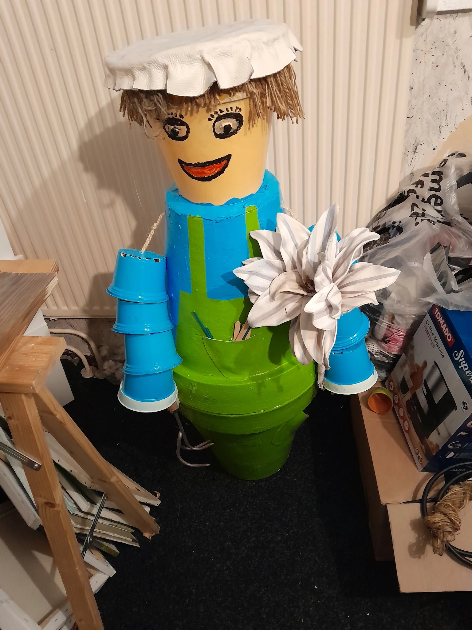 Decoratief object gemaakt van plastic emmers en potten in blauw en groen met kunstbloem