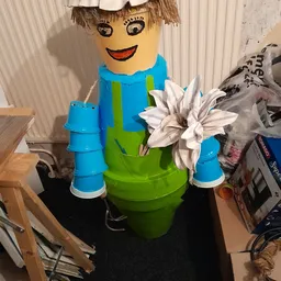 Decoratief object gemaakt van plastic emmers en potten in blauw en groen met kunstbloem