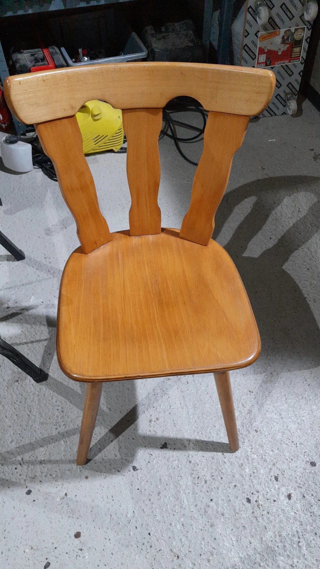 Houten stoel met gebogen rugleuning en zitblad, gefotografeerd van bovenaf op betonnen ondergrond.