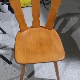 Houten stoel met gebogen rugleuning en zitblad, gefotografeerd van bovenaf op betonnen ondergrond.