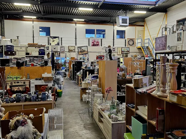 Ruim interieur van kringloopwinkel met diverse meubels, huishoudspullen en andere tweedehands goederen op stellingen en tafel