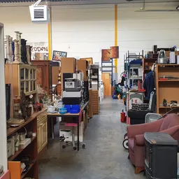 Overzicht van de winkelvloer met houten meubels, stellingen, dozen en diverse tweedehands spullen
