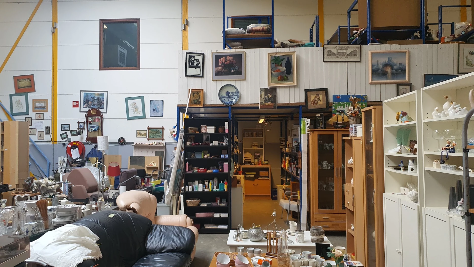 Winkelvloer met meubels, kasten, kunstwerken aan wand en diverse gebruiksartikelen in kringloopwinkel