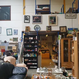 Winkelvloer met meubels, kasten, kunstwerken aan wand en diverse gebruiksartikelen in kringloopwinkel