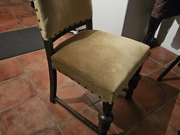 Tweedehands stoel met olijfgroene stofbekleding en zwart houten frame op terracottakleurige tegels