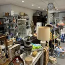 Overzicht van de winkelvloer met diverse spullen, meubels, lampen en huishoudartikelen op rekken en tafels