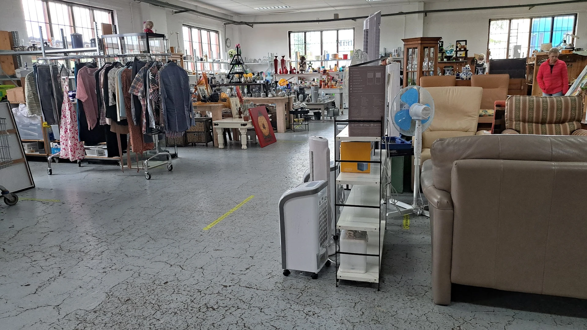 Winkelvloer met rekken tweedehands kleding links, meubels rechts en diverse spullen in het midden