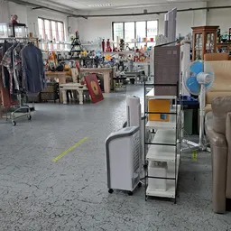 Winkelvloer met rekken tweedehands kleding links, meubels rechts en diverse spullen in het midden