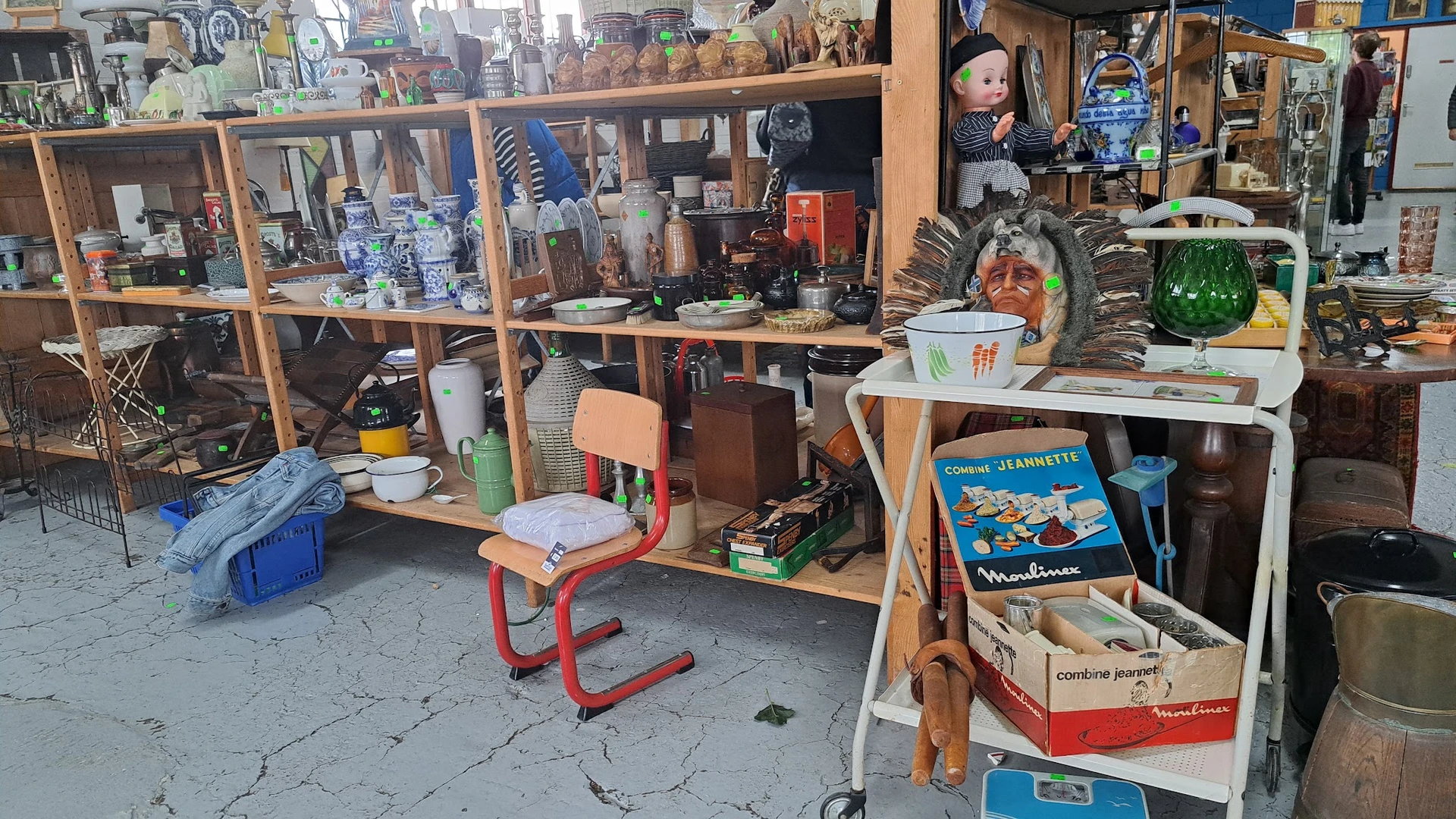 Winkelinterieur met houten stellingen vol diverse tweedehandsartikelen, spullen en decoraties