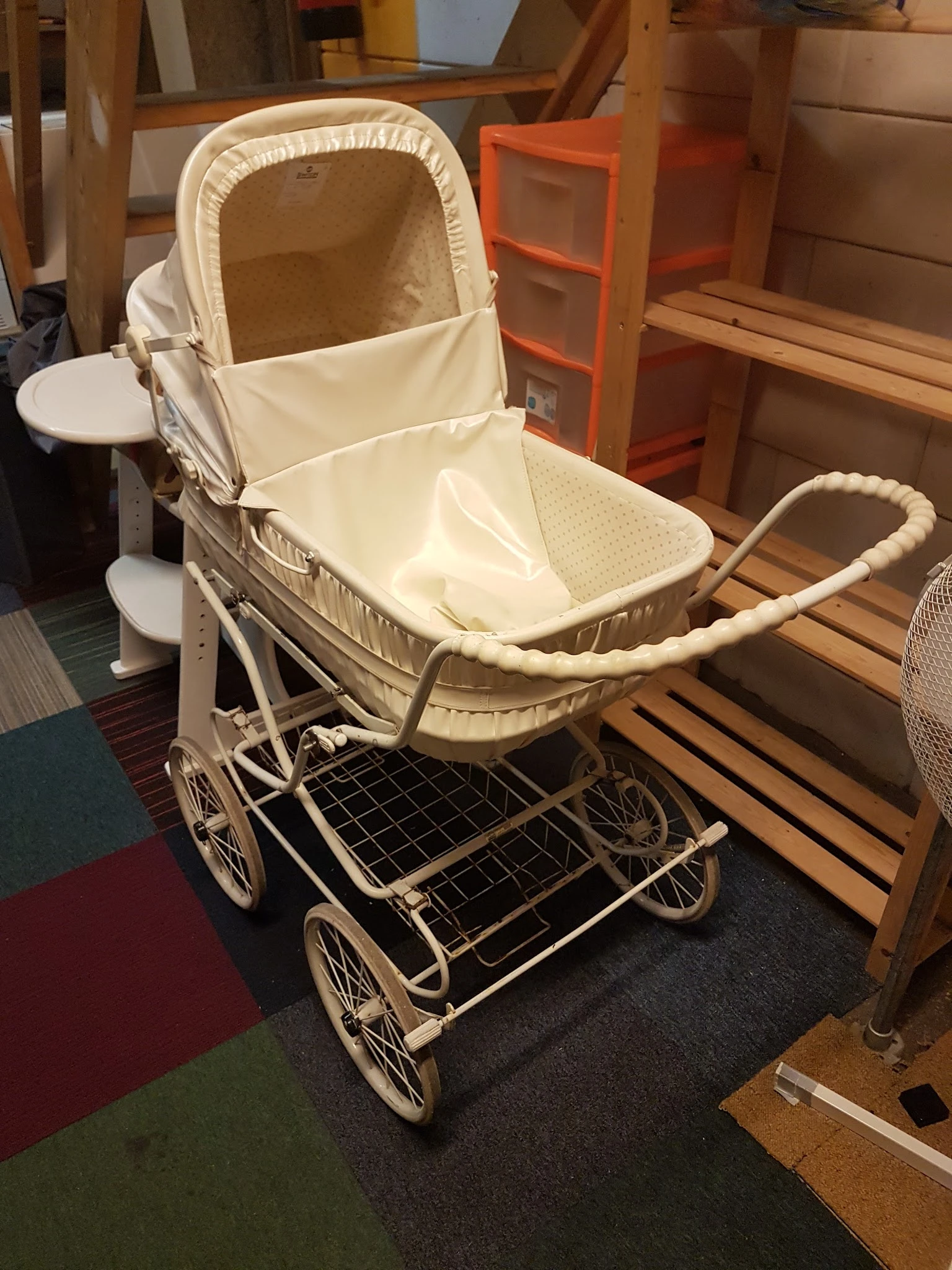 Vintage kinderwagen in crème-wit met zwart metalen onderstel, open verkocht in kringloopwinkel