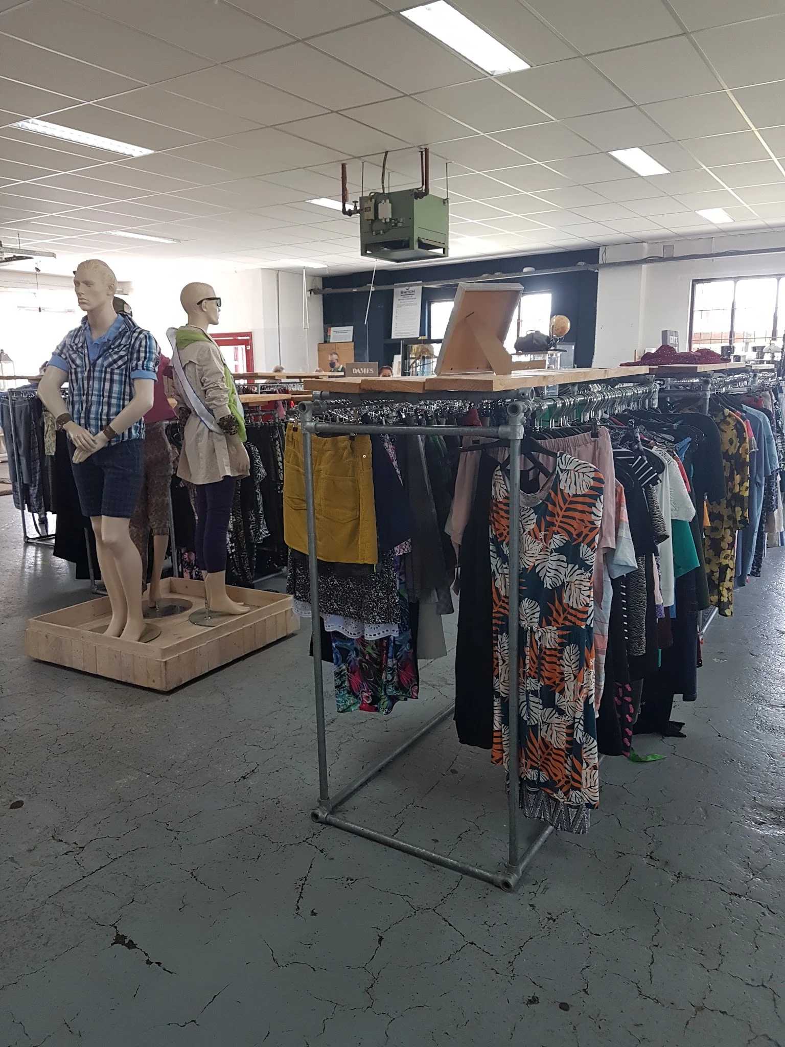 Rekken met tweedehands kleding en mannequins in kringloopwinkel