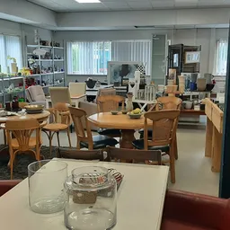 Ruim winkelbinnenland met houten meubels, stoelen, tafels en diverse huishoudartikelen uitgestald