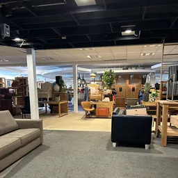 Winkelvloer met diverse meubels en huishoudartikelen uitgestald, waaronder kasten, stoelen, lampen en decorstukken