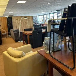 Winkelvloer met meubels: gele fauteuil, houten tafel, zwarte stoelen en kasten, arc lamp en glazen vitrinekast