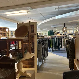 Winkelinterieur met kledingrekken, kastjes en verlichte plafondafwerking