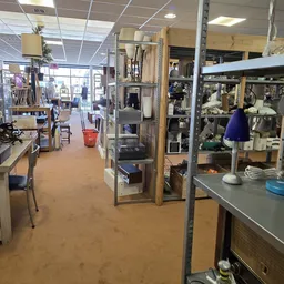 Winkelvloer met stellingen, werkplekken en uiteenlopende spullen in een kringloopwinkel
