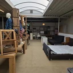 Winkelvloer met meubels: houten stellage met kleding, bedden, bank en diverse meubelstukken