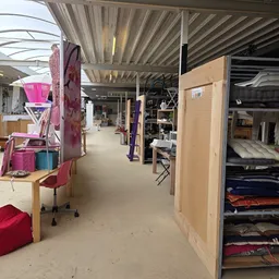 Winkelvloer van kringloopwinkel met stellingen, meubels en diverse spullen langs de muren