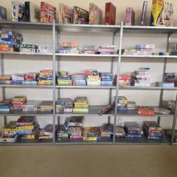 Metalen stellingen vol met bordspellen, puzzels en ander speelgoed in een kringloopwinkel
