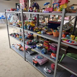 Metalen stellingen vol met speelgoed, poppen, actiefiguren en ander kinderspeelgoed in diverse kleuren