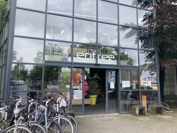 Glazen gevel van kringloopwinkel 2Switch met 'entree' letters en fietsen geparkeerd ervoor