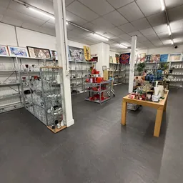 Overzicht van kringloopwinkel met glazen vitrinekasten, stellingen en houten tafel met merchandise