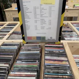 Prijslijst met Euro-bedragen en Switch-logo op houten toonbank met cd's