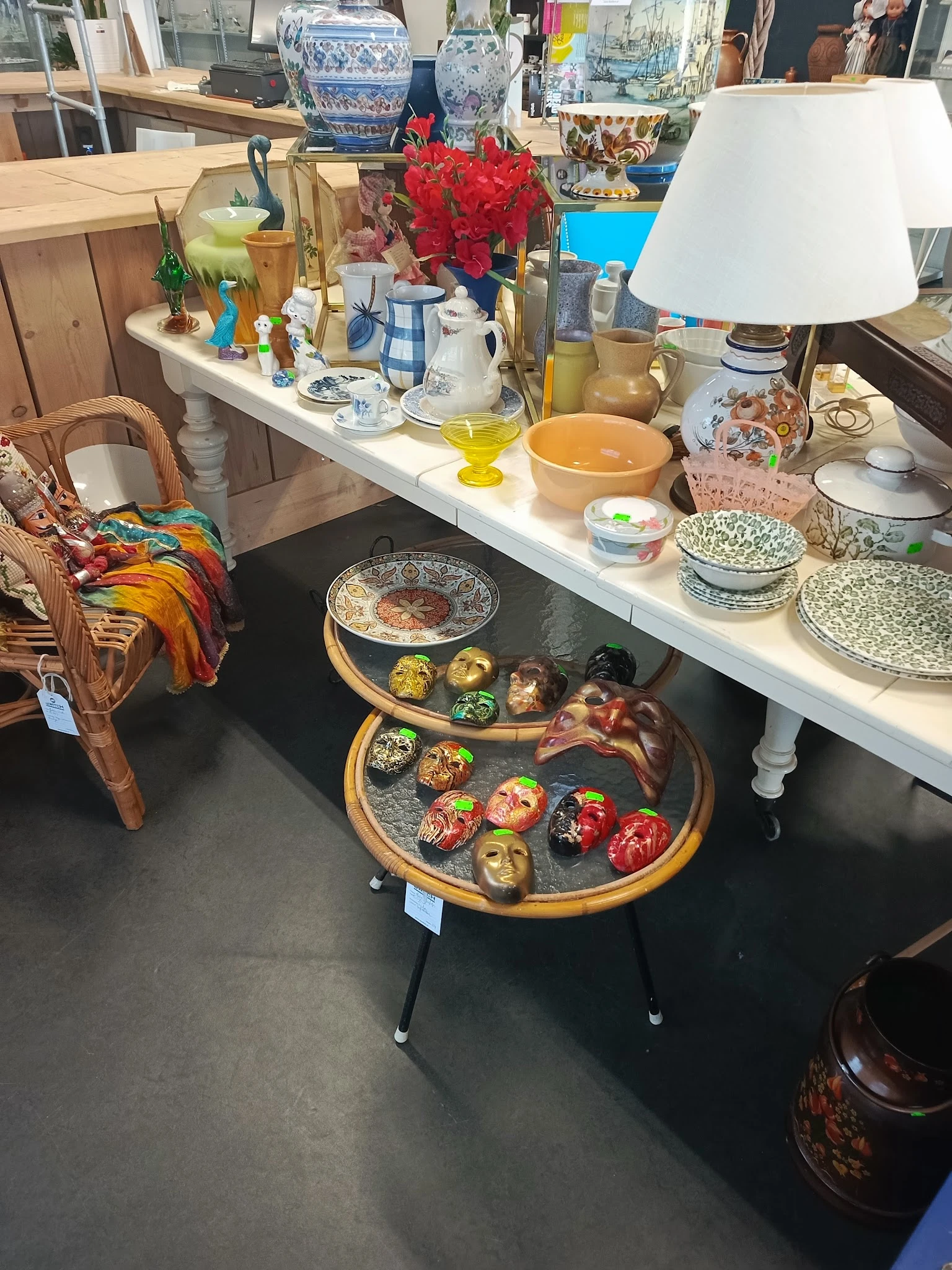 Uitgestalde decoratieve items op tafels, waaronder beschilderde schalen en serviesgoed