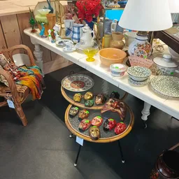 Uitgestalde decoratieve items op tafels, waaronder beschilderde schalen en serviesgoed