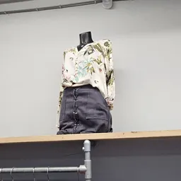 Close-up van een tweedehands rugzak met bloemenprint en zwarte zijkanten op een houten plank