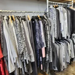 Rekken met tweedehands kleding in verschillende kleuren en patronen