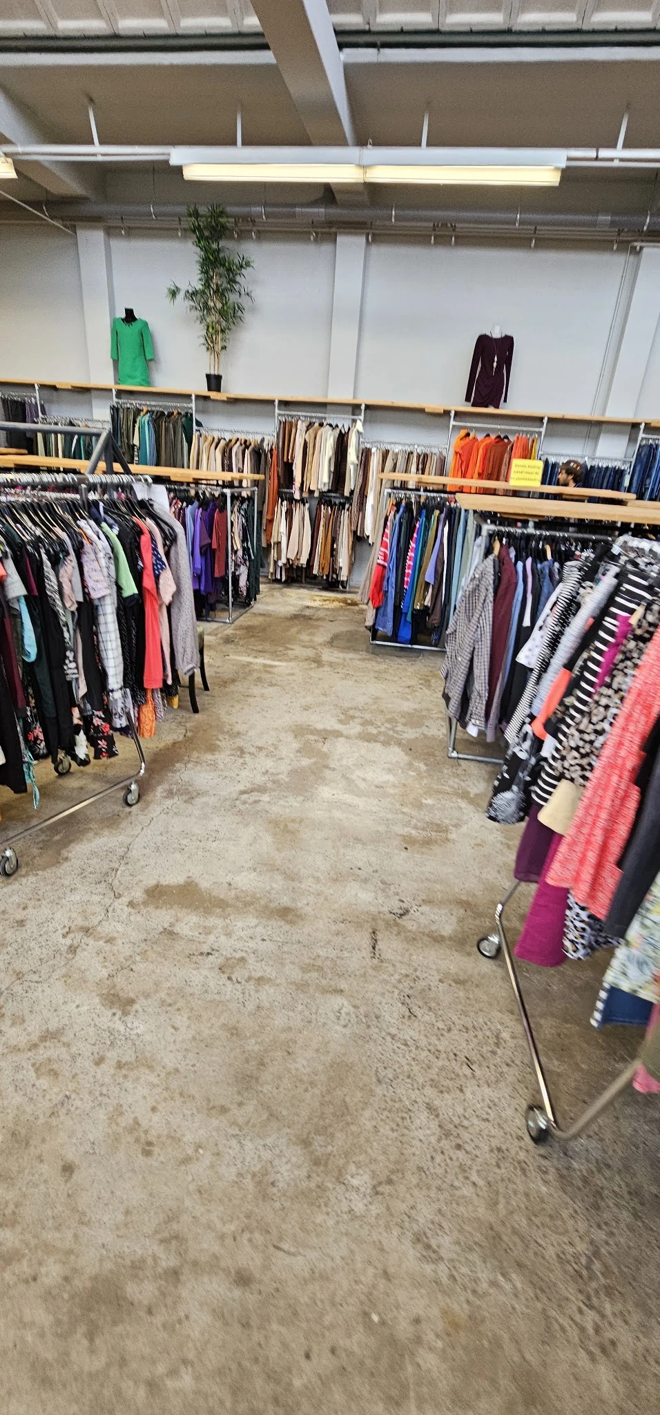 Kringloopwinkel met rekken vol tweedehands kleding langs beide zijden van het gangpad