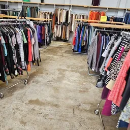 Kringloopwinkel met rekken vol tweedehands kleding langs beide zijden van het gangpad