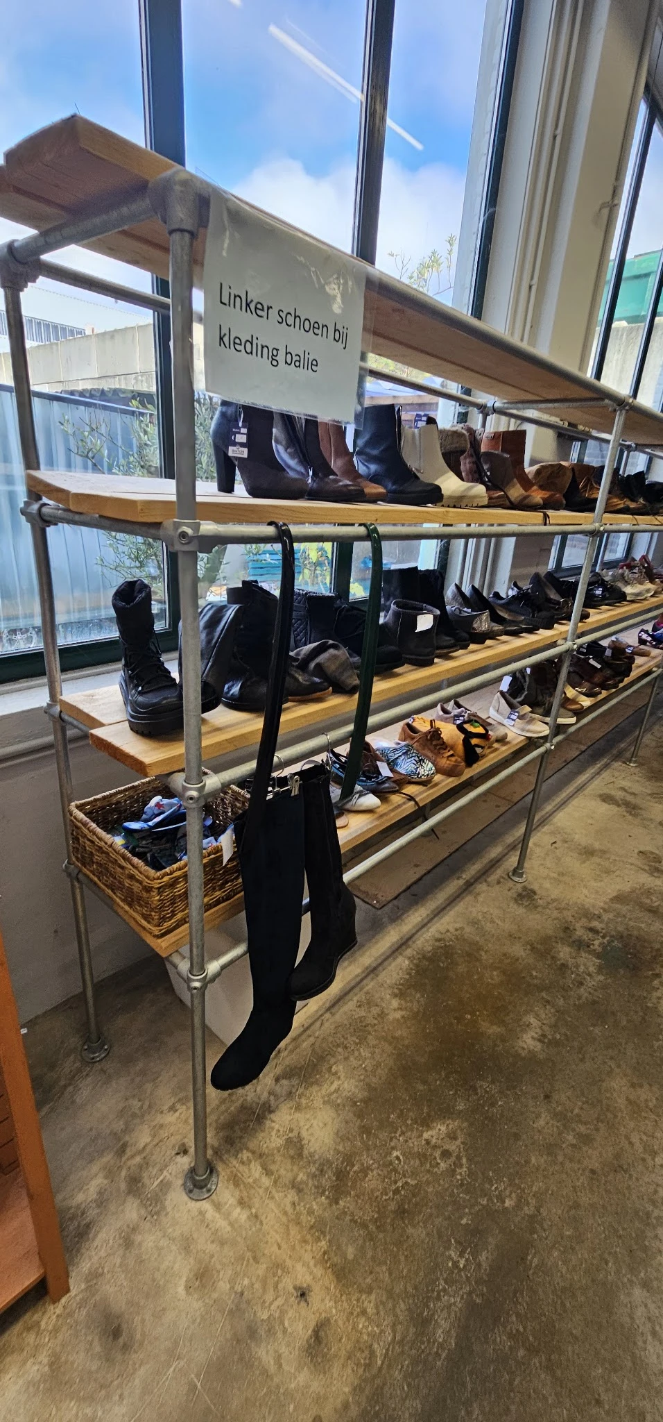 Stellingen met uitgestalde tweedehands schoenen en laarzen in verschillende kleuren en stijlen