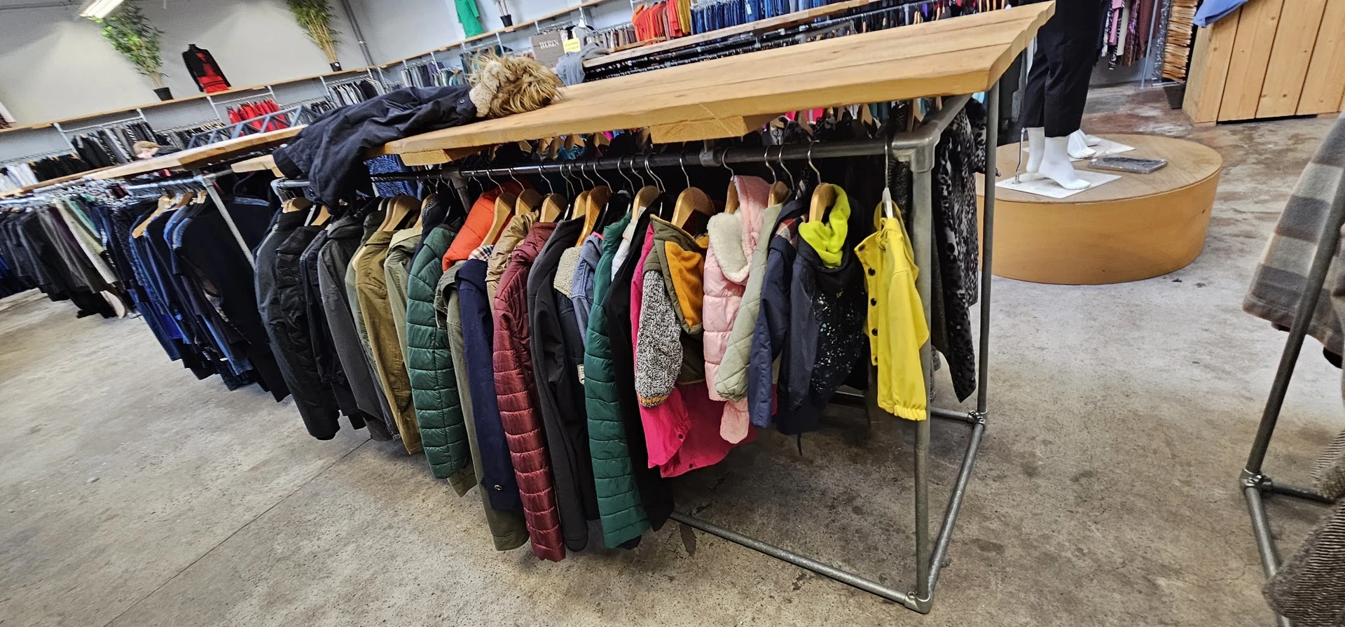 Rek met diverse tweedehands winterjassen en jacks op hangers in de winkel