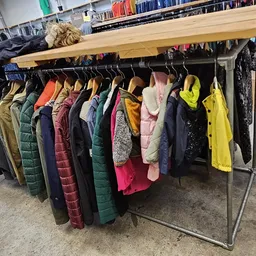 Rek met diverse tweedehands winterjassen en jacks op hangers in de winkel