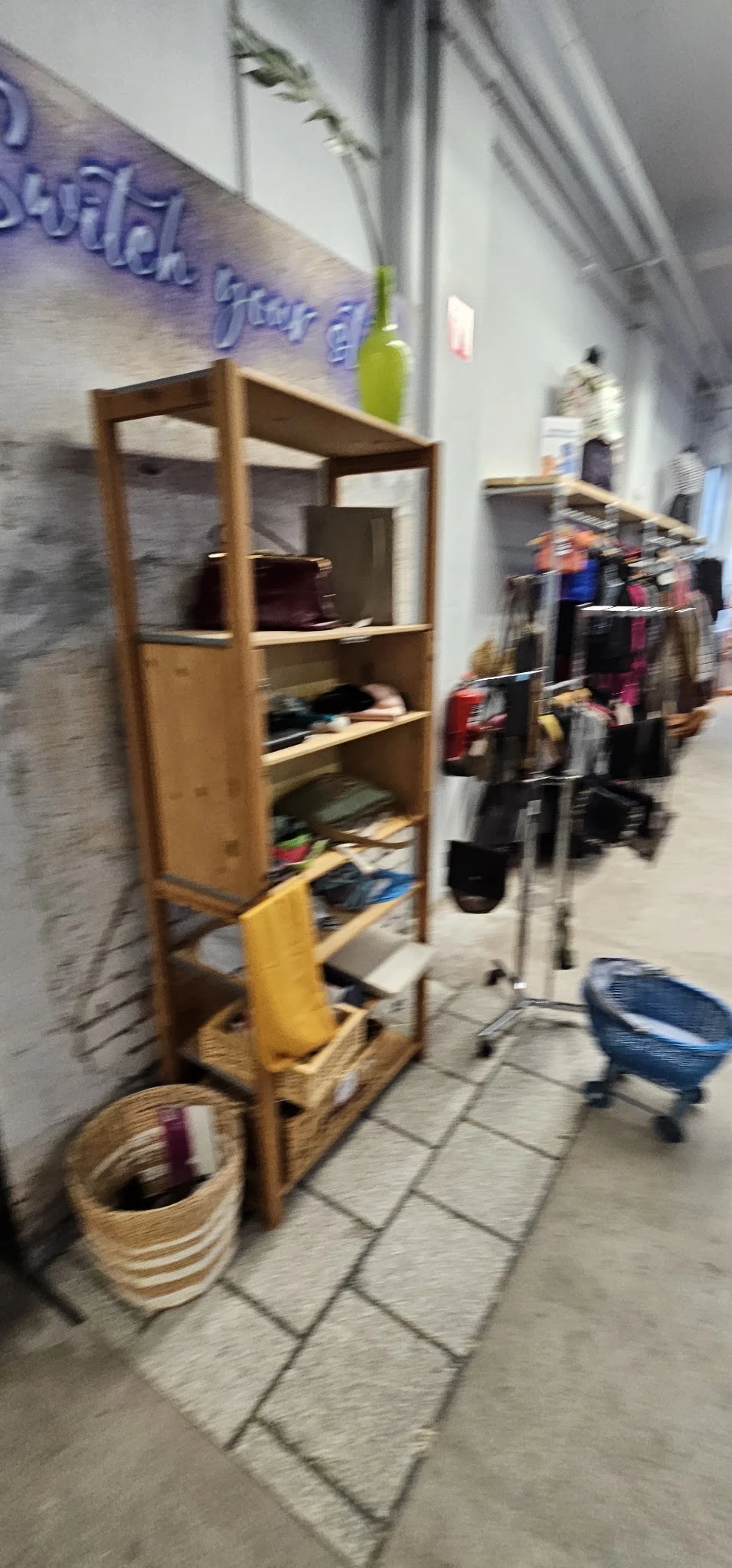 Houten stellingen met kleding en spullen in een kringloopwinkel, foto is onscherp