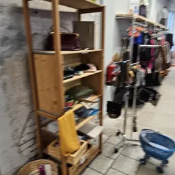 Houten stellingen met kleding en spullen in een kringloopwinkel, foto is onscherp