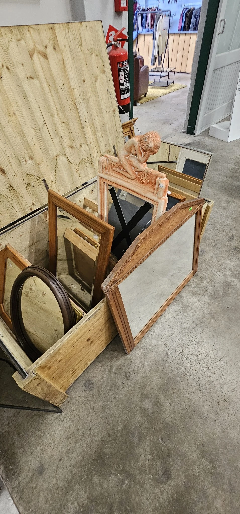 Verschillende spiegels en houten frames uitgestald op betonnen vloer