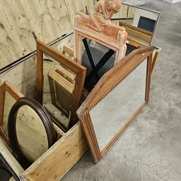 Verschillende spiegels en houten frames uitgestald op betonnen vloer