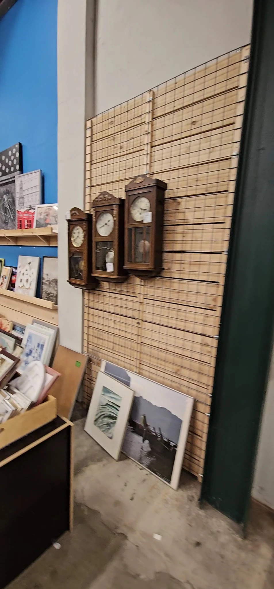 Wandklok en houten slatwall met uitgestalde items in kringloopwinkel