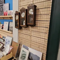 Wandklok en houten slatwall met uitgestalde items in kringloopwinkel