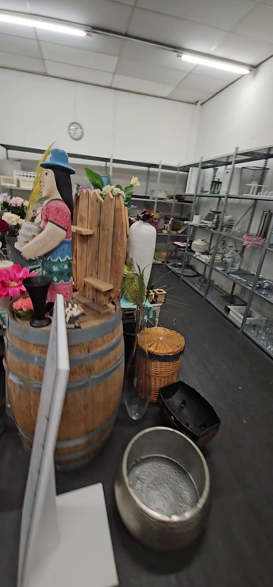 Diverse tweedehands artikelen zoals bloemen, houten decoratiestukken, manden en servies op display