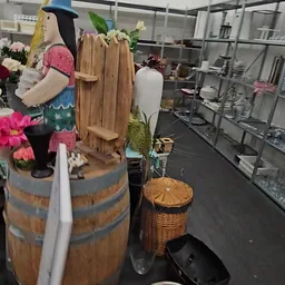 Diverse tweedehands artikelen zoals bloemen, houten decoratiestukken, manden en servies op display